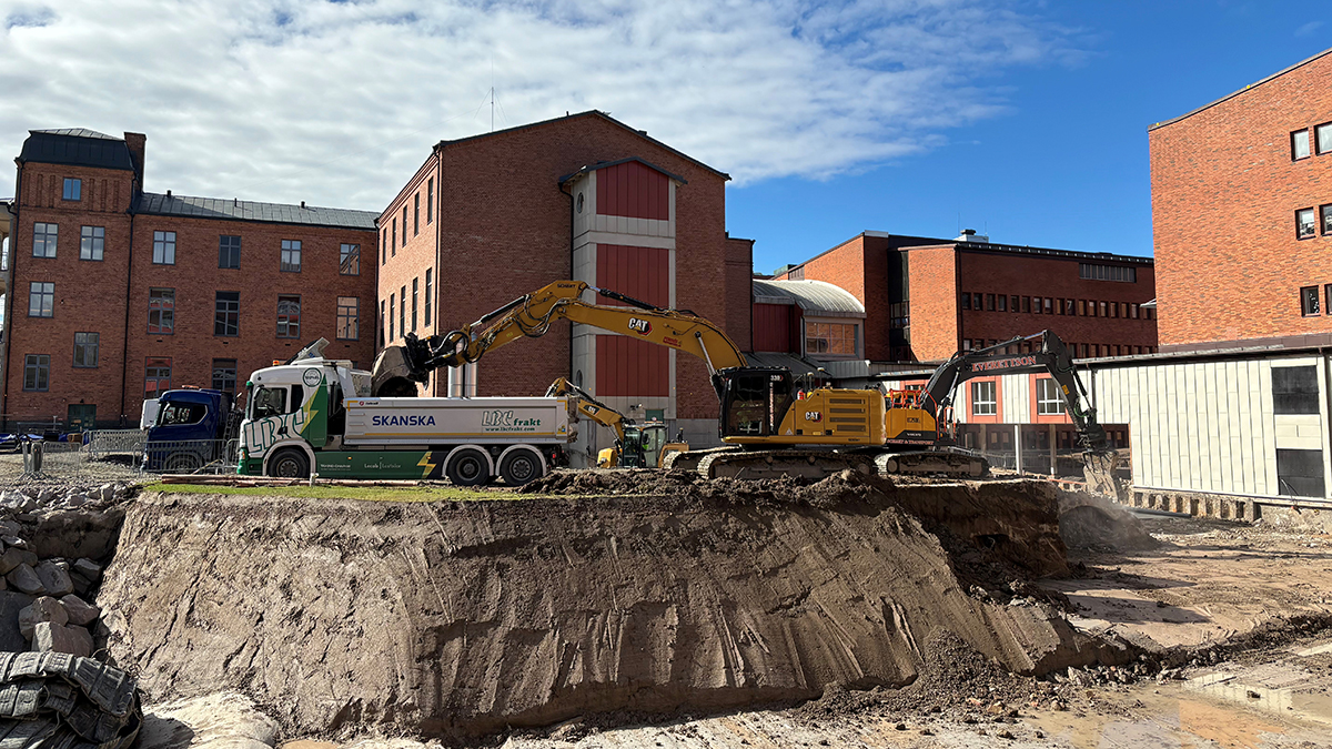 Bild på elektrisk lastbil som lastas av en grävmaskin utanför Centralsjukhuset i Karlstad. På lastbilen står: LBC Frakt och Skanska