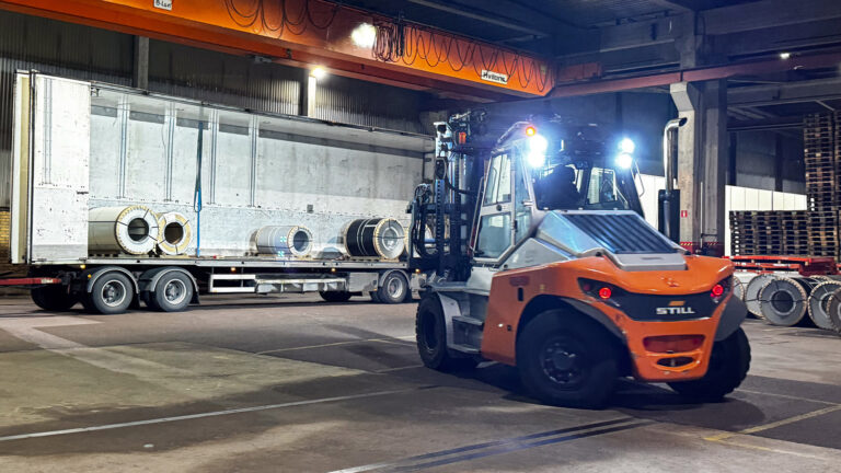 Bild på Truck - LBC Frakts lager som lastarv tunga metallrullar på en lastbil med släp.
