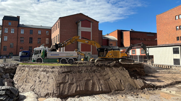 Bild på grusbil -LBCFrakt, som blir avlastad av en grävmaskin på bygget av Nya Centralsjukhuset Karlstad.