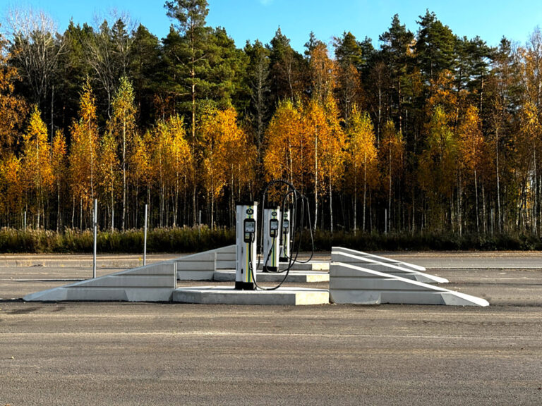 Bild på laddstation i Bråtebäcken Karlstad. Tre laddstolpar på en asfalterad plan med skog i bakgrunden.