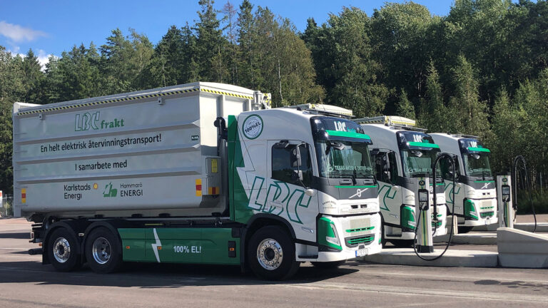 Tre elektrifierade lastväxlare med flak som laddar. Flak med texten: LBC Frakt en helt elektrisk återvinningstransport! i samarbete med Karlstads Energi och Hammarö Energi.