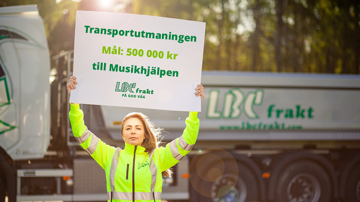 En ung tjej i varselkläder står framför en lastbil. Hon håller upp en skylt med texten: Transportutmaningen. Mål:500 000 kr till Musikhjälpen. LBC Frakt på god väg.