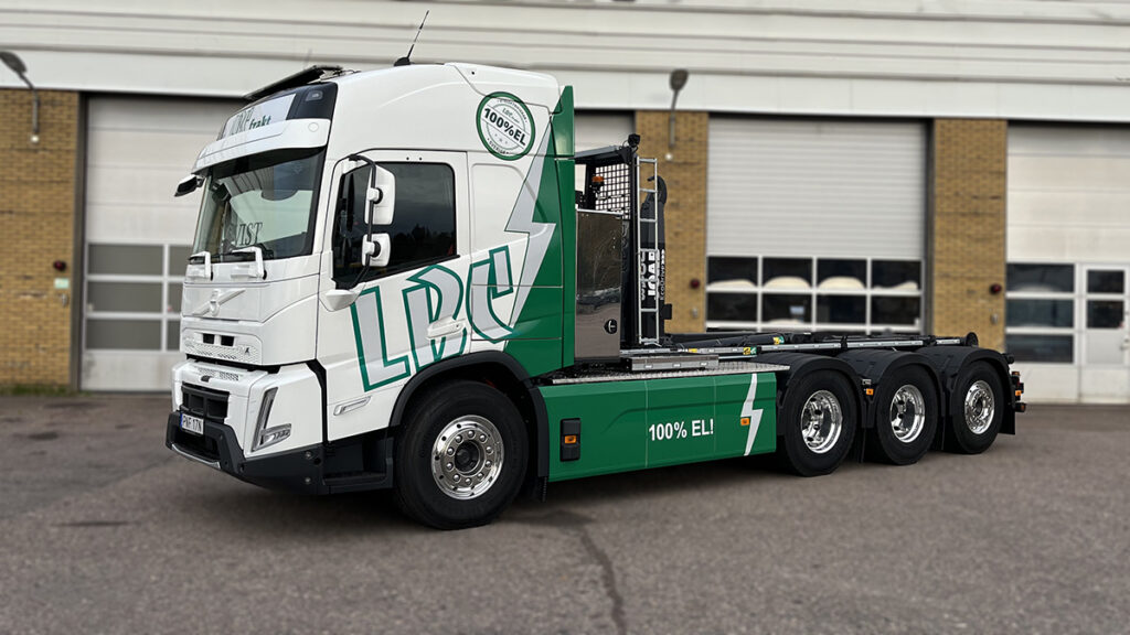 Bild på en av LBC Frakts eldrivna lastbilar. Lastbilen står parkerad framför ett garage.