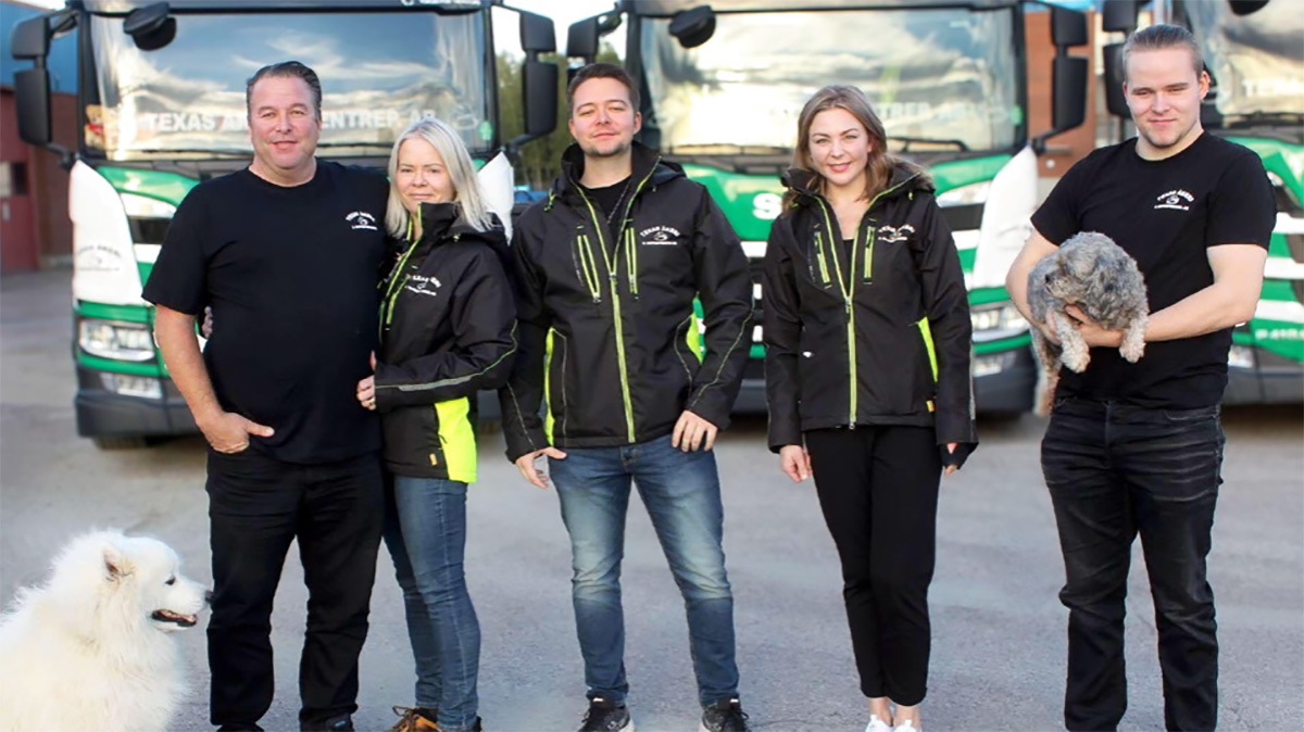 Ägare och anställda till Texas Åkeri & Entreprenad står på rad med tre stycken LBC Frakt lastbilar i bakgrunden